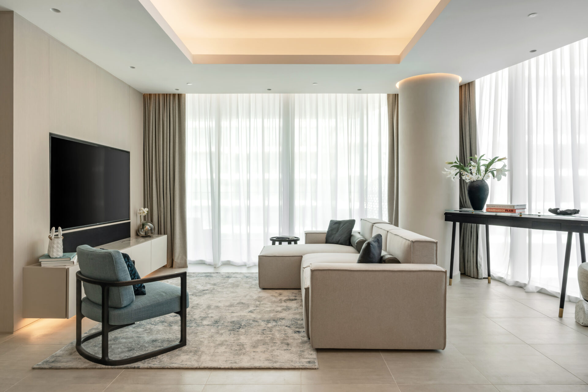 Modern living room in Serenia Residences, Palm Jumeirah, with custom media wall, neutral sectional sofa, and accent armchair.