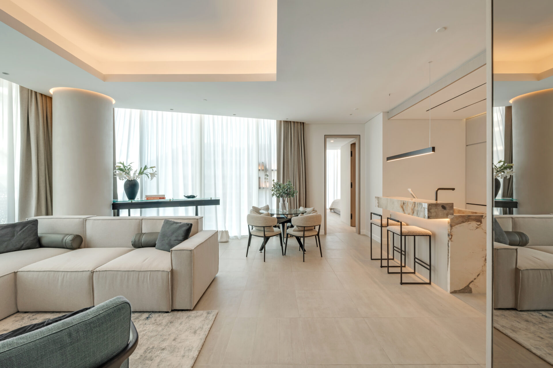 Spacious open-plan living area with neutral sectional sofa, round dining table, and marble breakfast bar in Serenia Residences, Palm Jumeirah.