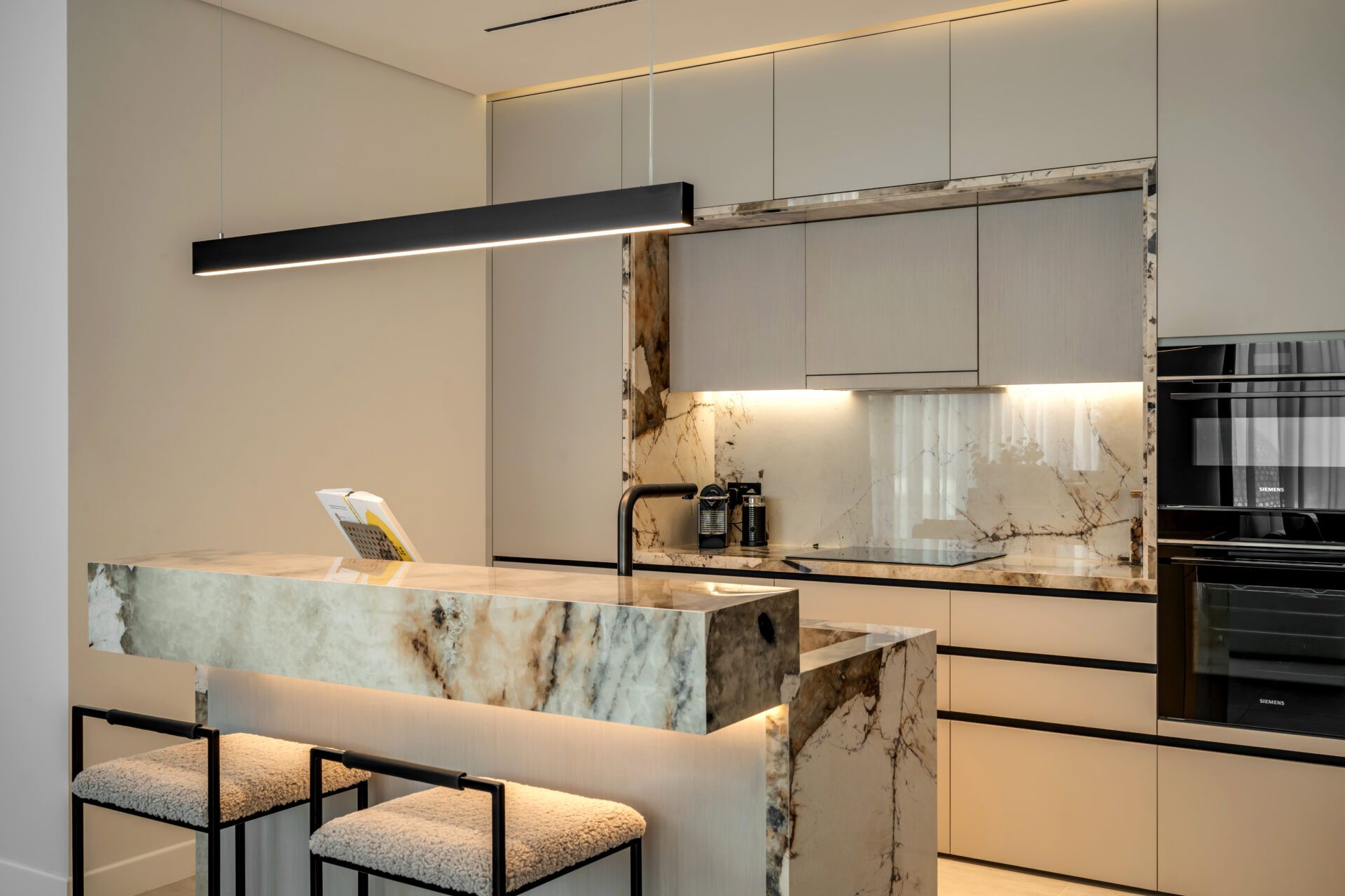 Luxury kitchen in Serenia Residences, Palm Jumeirah, with marble breakfast bar, integrated appliances, and sleek handleless cabinetry.