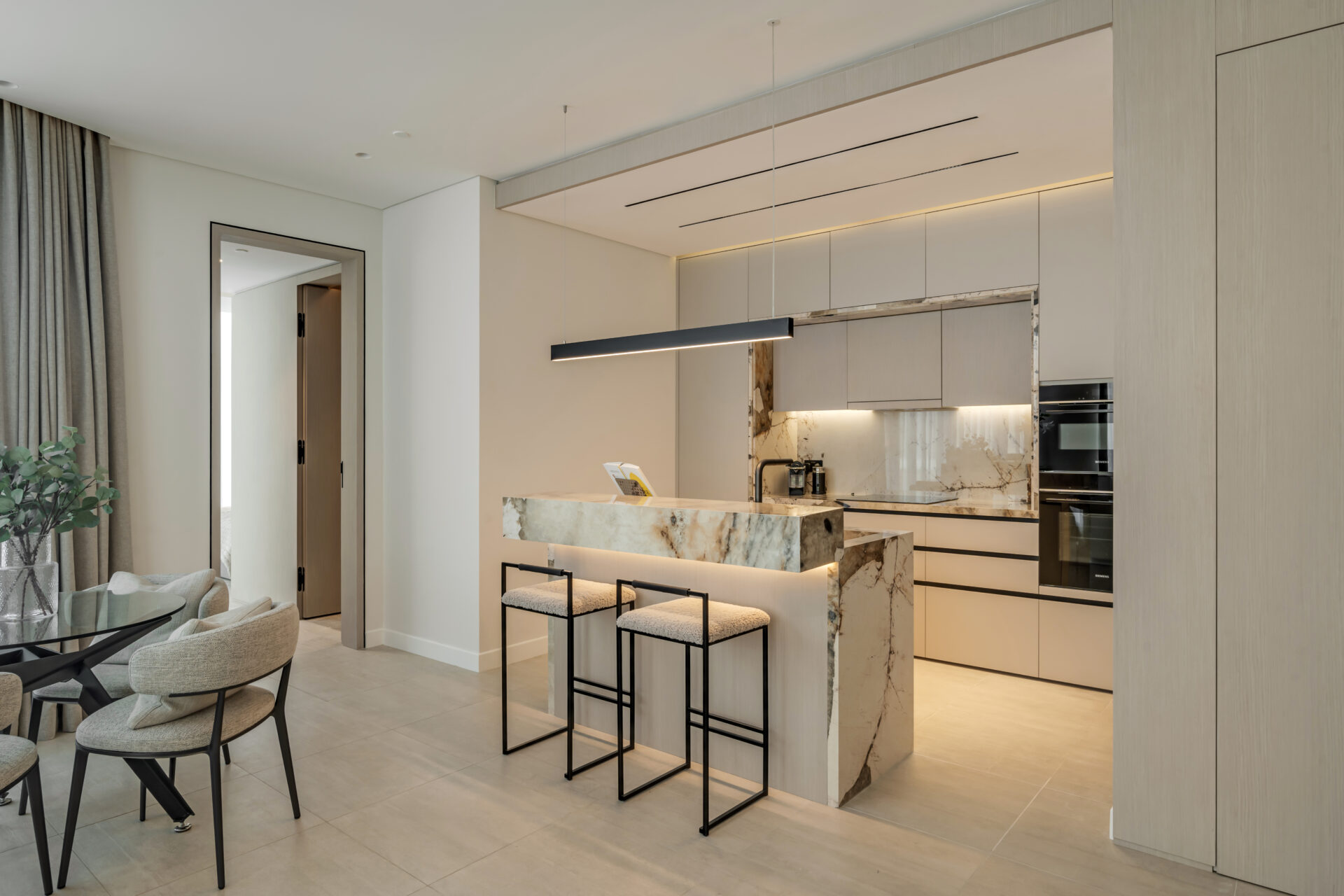 Luxury open-plan kitchen with marble breakfast bar, modern pendant light, and dining area in Serenia Residences, Palm Jumeirah.