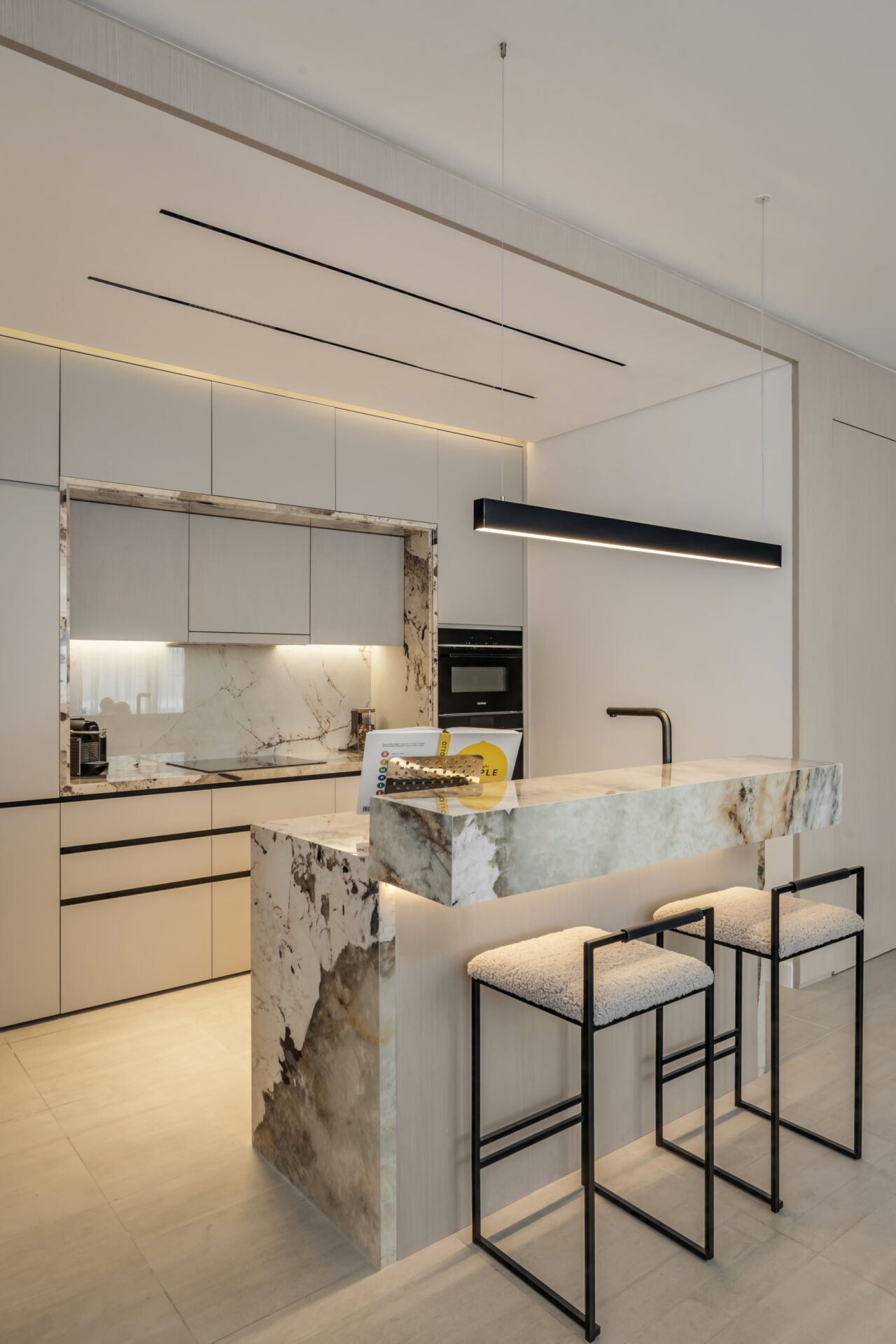 Close-up of luxury kitchen with marble breakfast bar, sleek cabinetry, and modern pendant lighting in Serenia Residences, Palm Jumeirah.