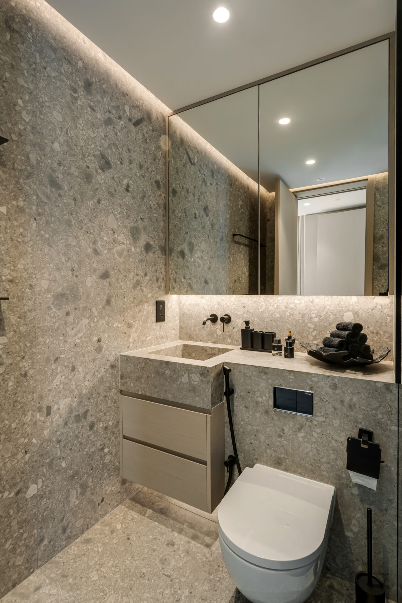 Modern bathroom with grey terrazzo walls and floors, floating vanity, and wall-mounted toilet.