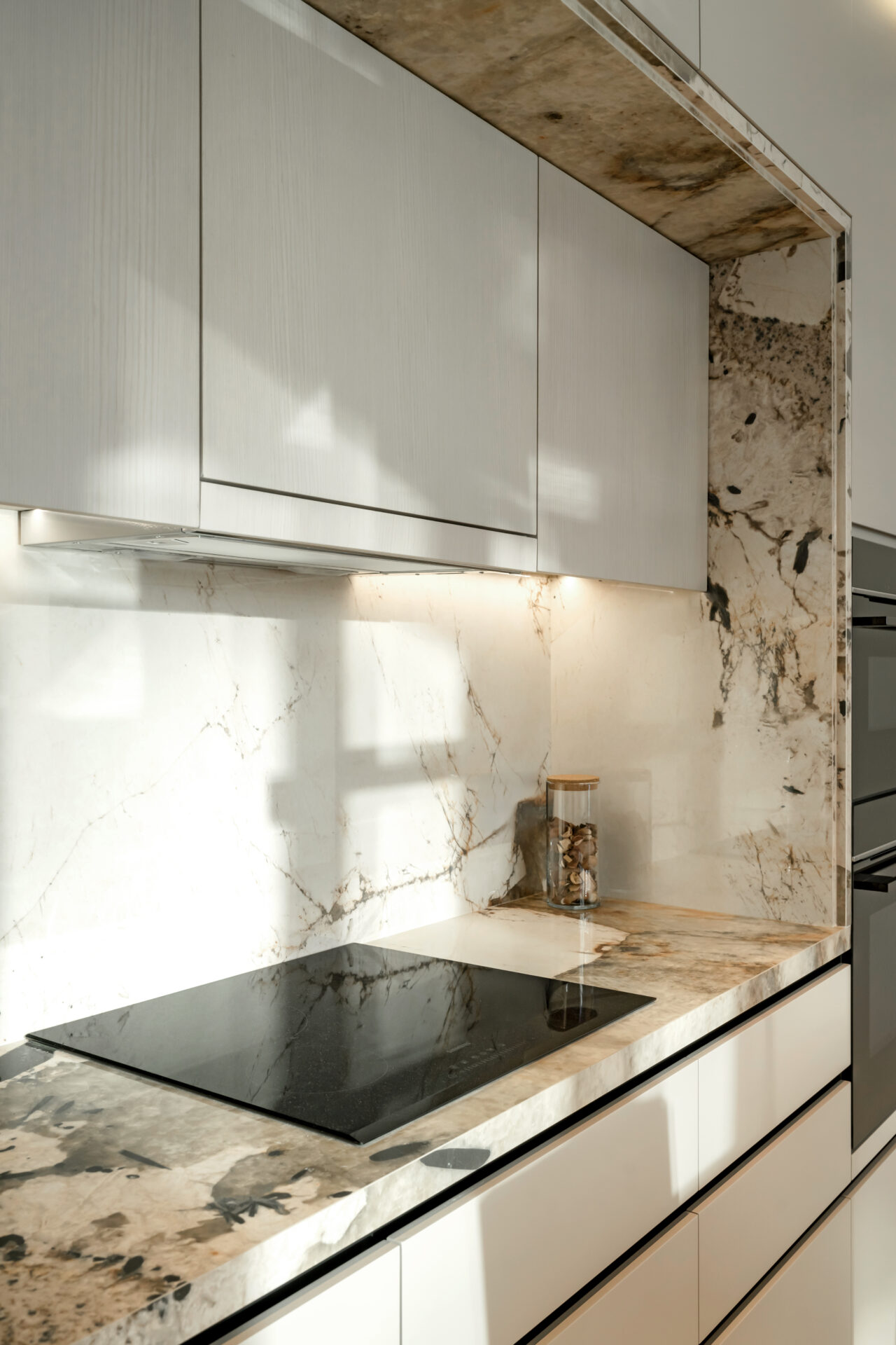 Close-up of marble kitchen countertop and backsplash with induction hob at Serenia Residences, Palm Jumeirah.