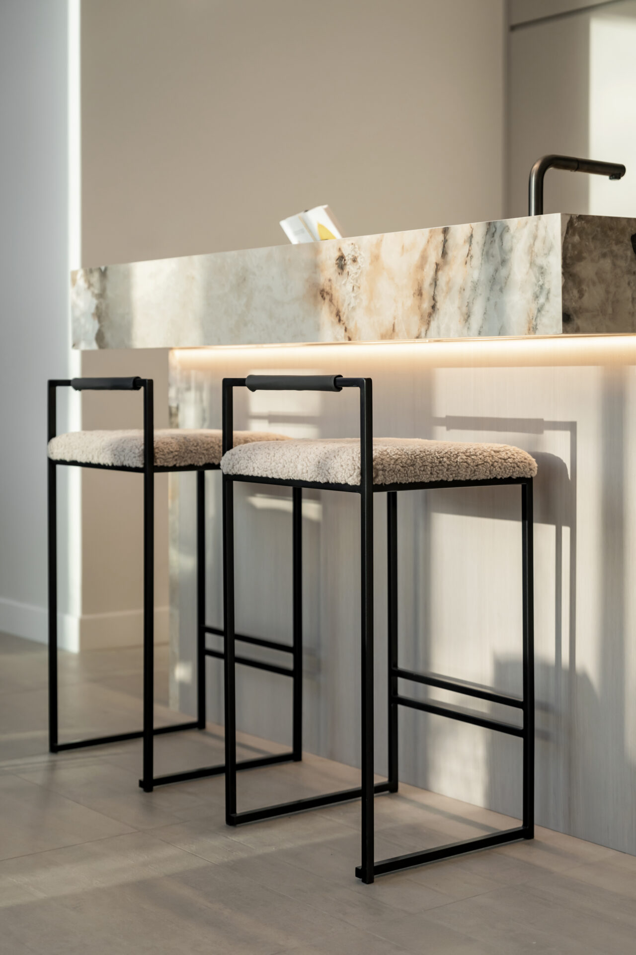 Wide kitchen view showing marble island, bar stools, and full cabinetry wall.