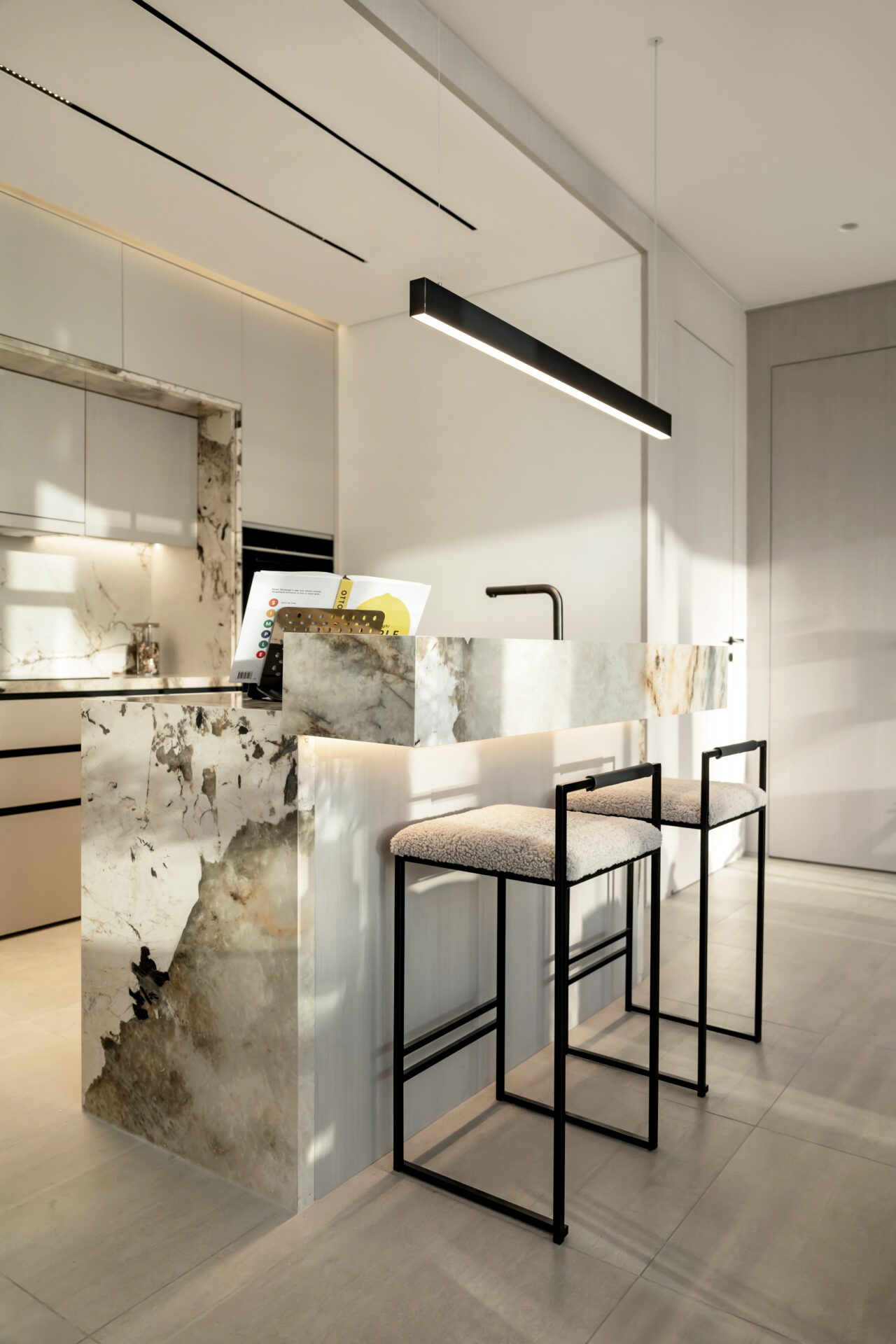 Luxury open-plan kitchen with a statement marble breakfast bar, modern pendant lighting, and minimalist bar stools in Serenia Residences, Palm Jumeirah.