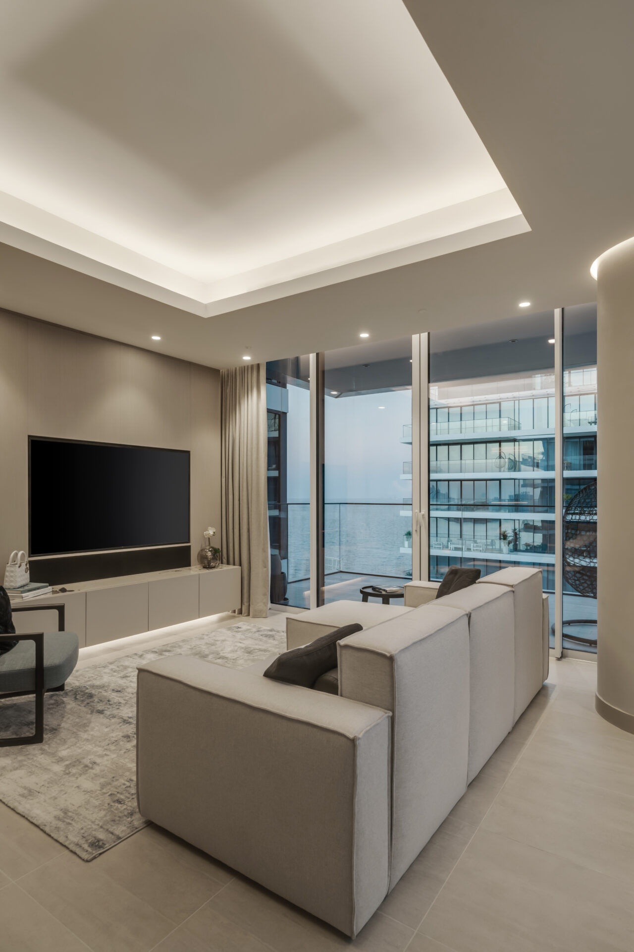 Luxury living room in Serenia Residences, Palm Jumeirah, with custom media wall, neutral sofa, and floor-to-ceiling windows overlooking the sea.